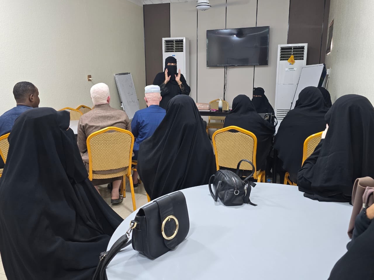 مدربة تتحدث أمام المشاركين والمشاركات الجالسين في قاعة التدريب